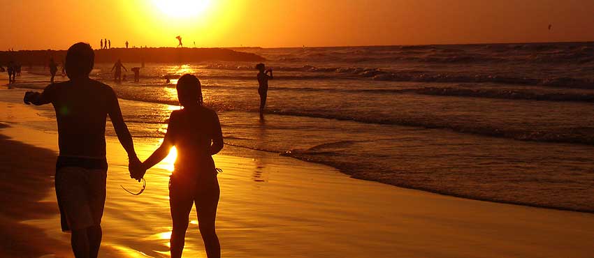 Romantyczny spacer zakochanej pary na plaży w trakcie zachodzącego słońca