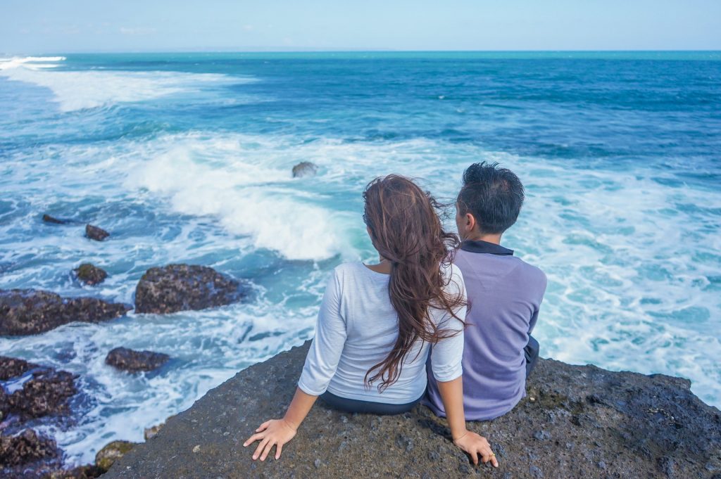 Dziewczyna rozmawia z chłopakiem podczas obserwowania fal morskich na wycieczce