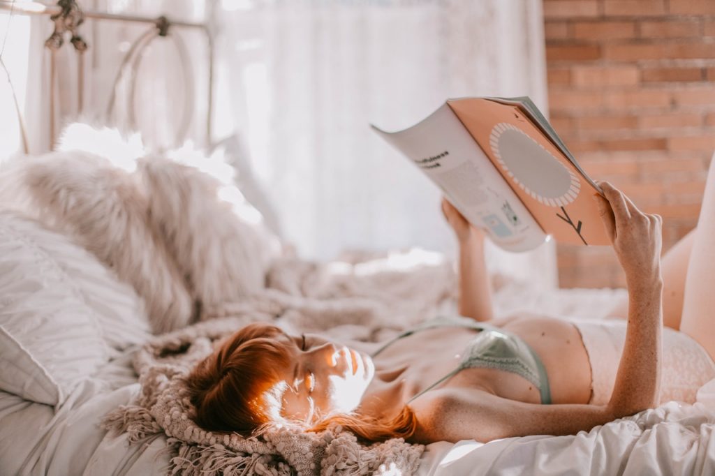 słodka ruda nastolatka leży w łóżku i czyta magazyn